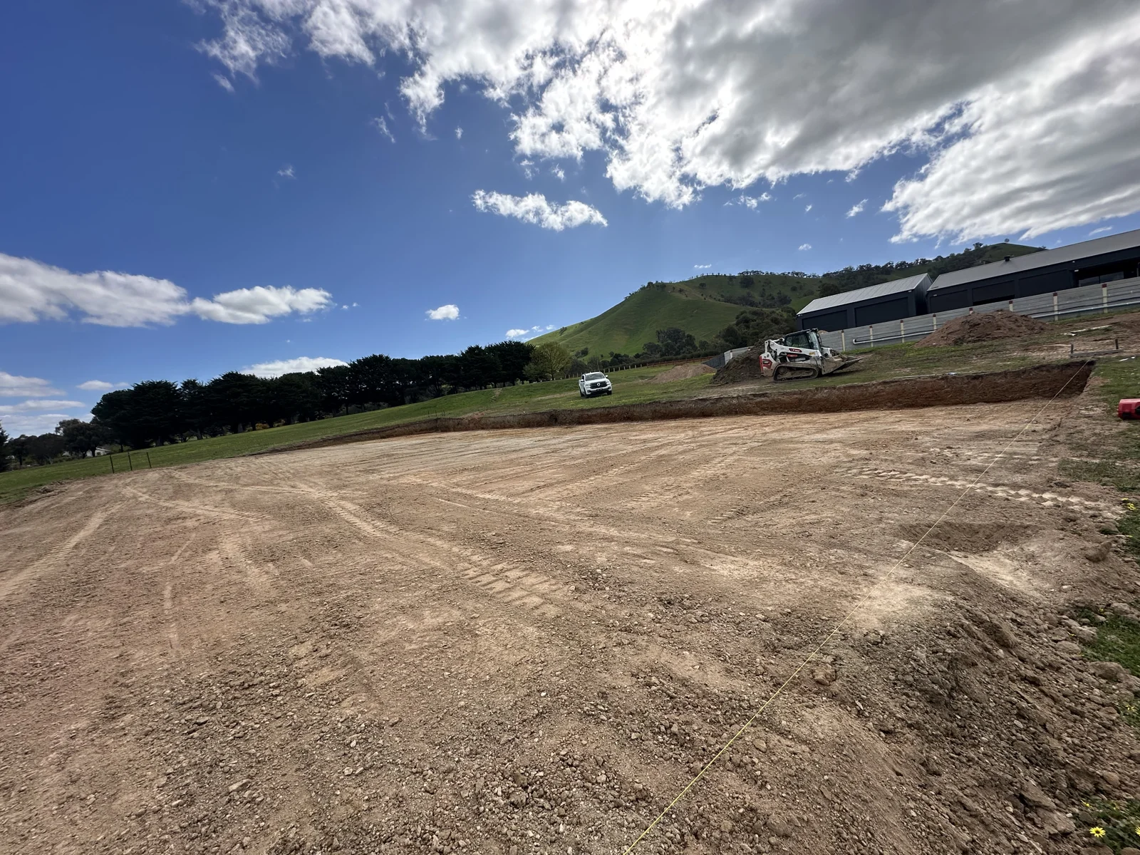 Entire Excavations — earthworks site cut with excavator, hills backdrop