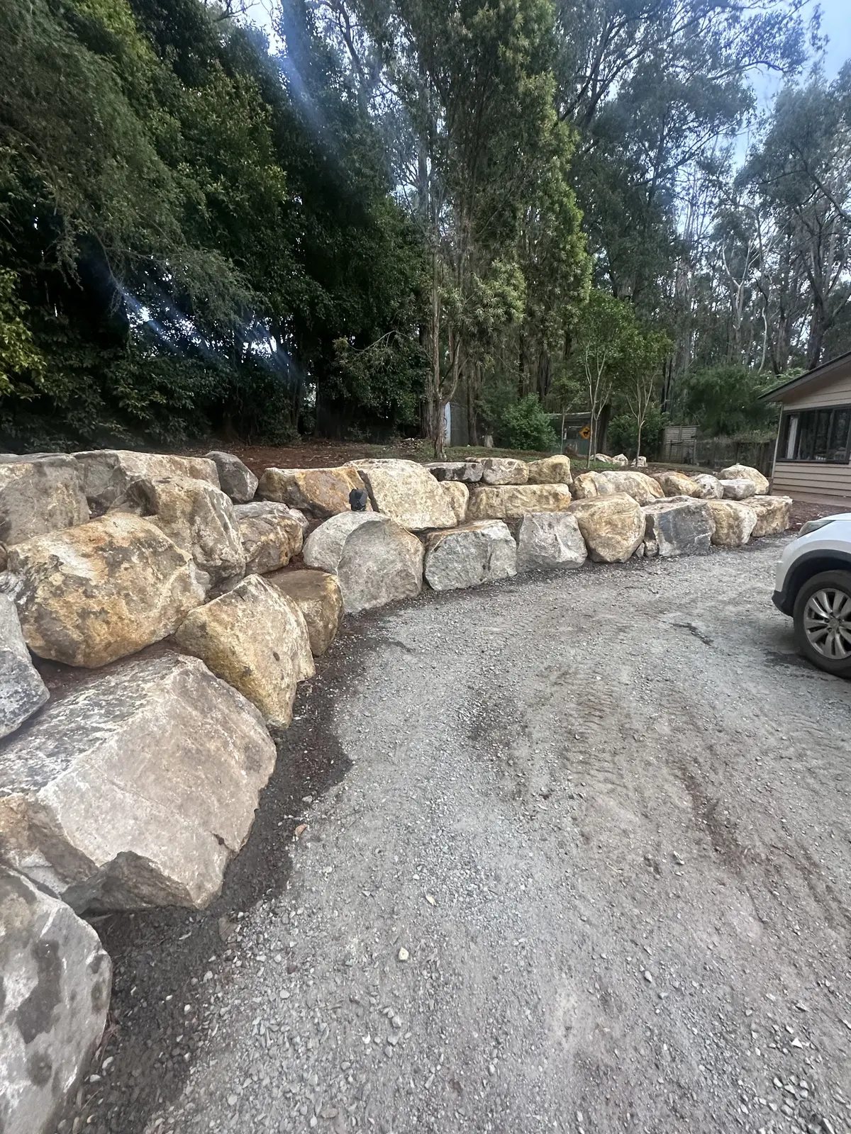Rockwall bordering a gravel driveway